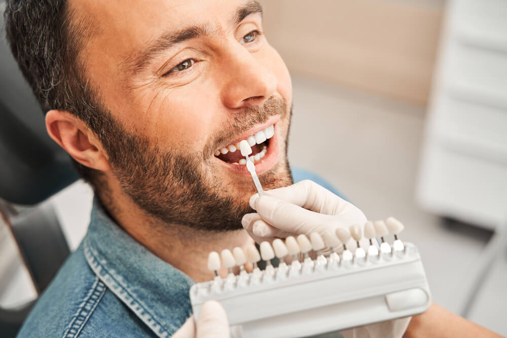 Dentist choosing color of tooth enamel in patient